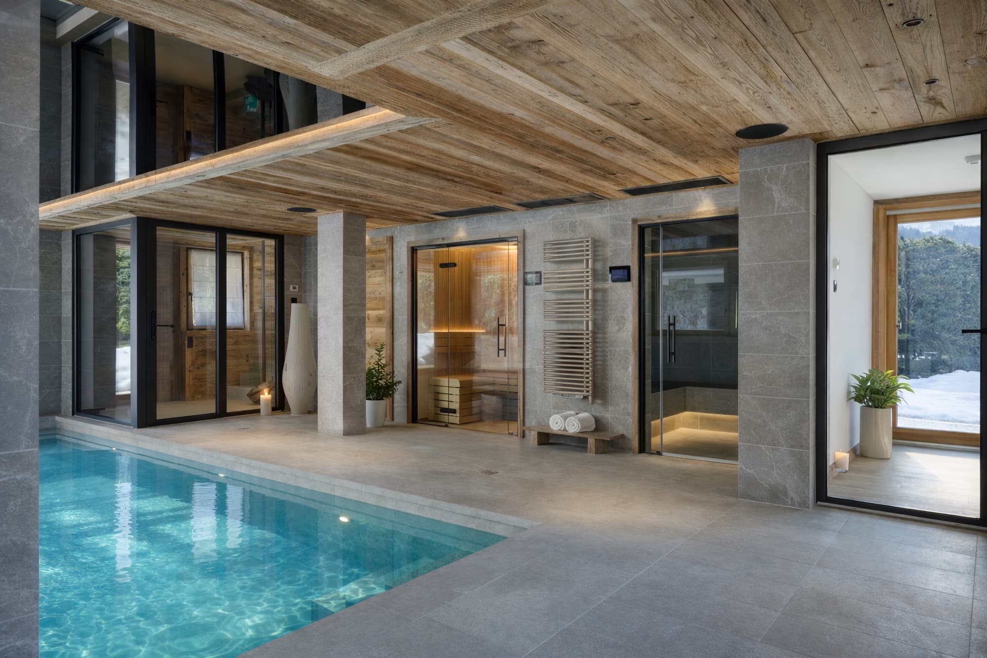 Piscine intérieure chauffée bordée de pierre et de bois